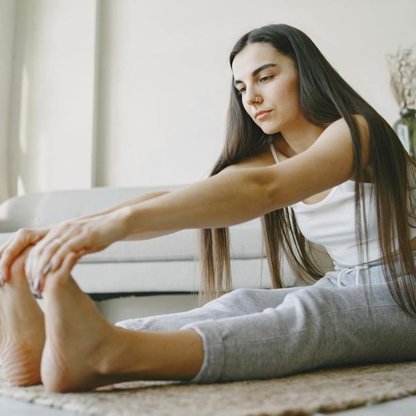 Woman performing a light stretching exercise in a bright room.
